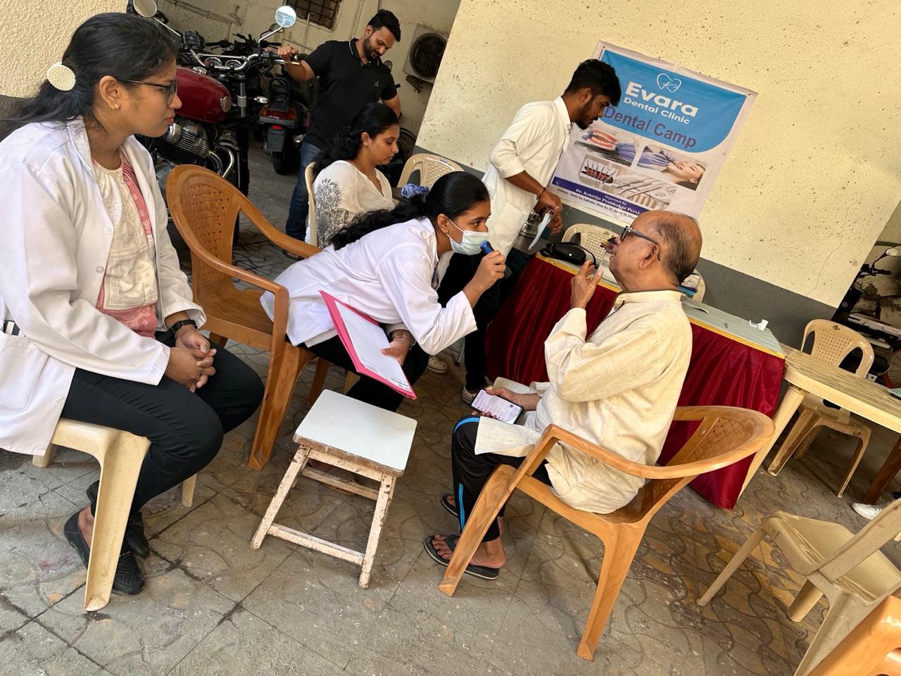 A dentist examining an elderly patient at an Evara community dental camp
