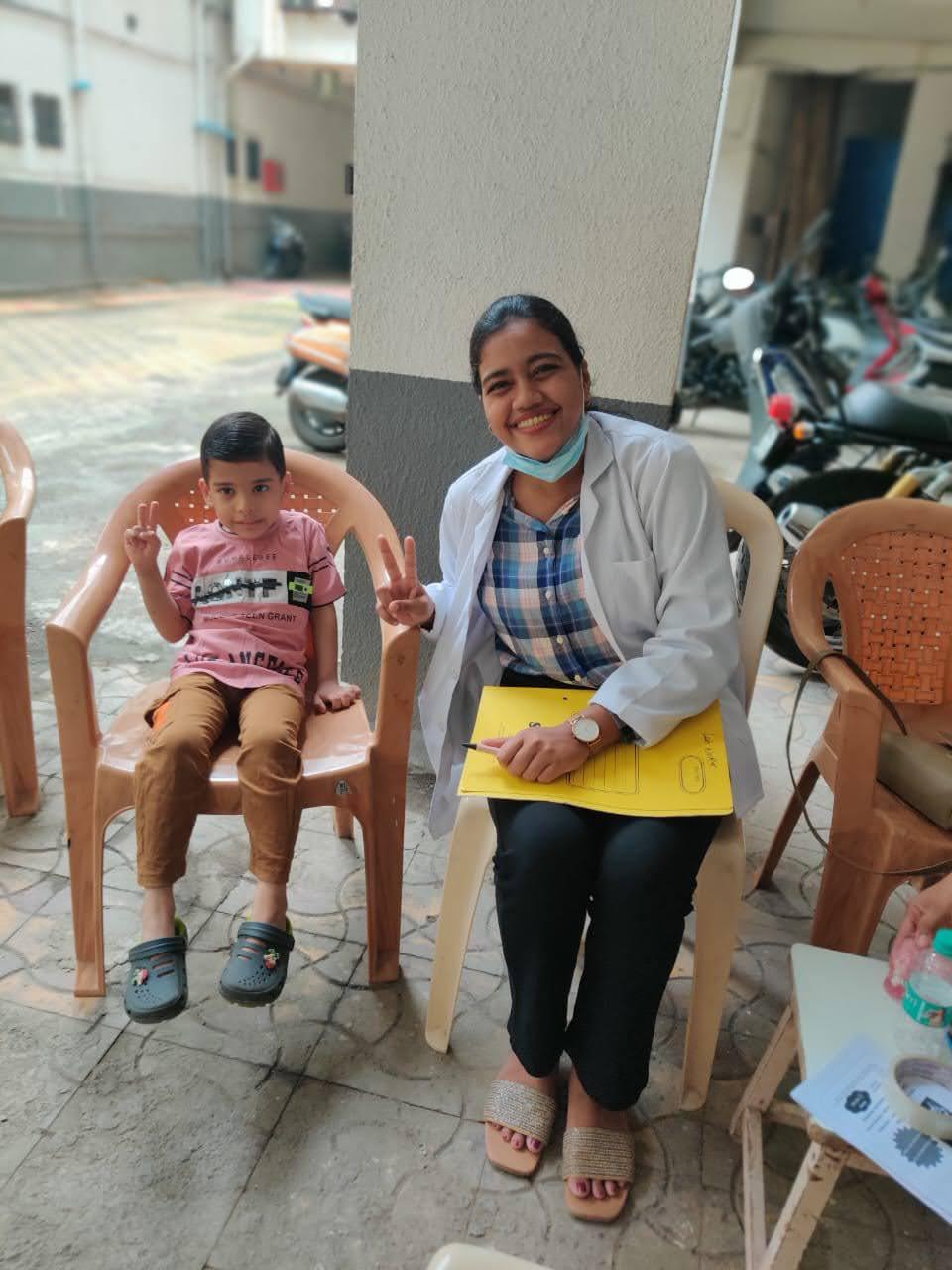 A smiling dentist and a young patient after a check-up at a community dental camp