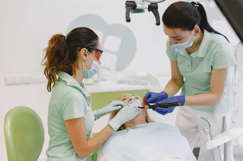 Two dentists placing a tooth-coloured filling for a patient