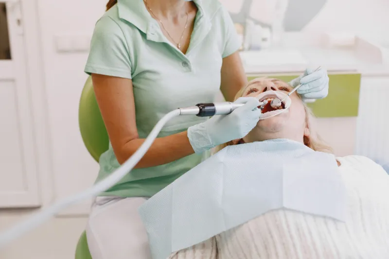 A dental hygienist cleaning a patient's teeth and gums