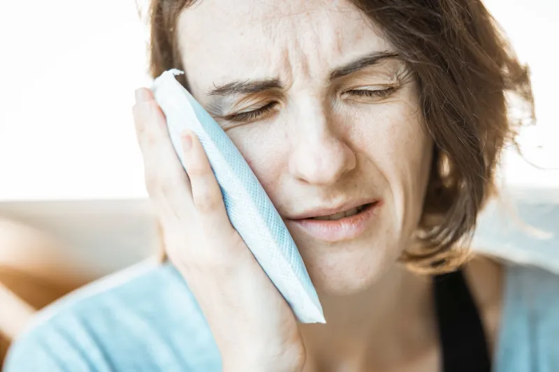 A person holding an ice pack to their jaw with a toothache